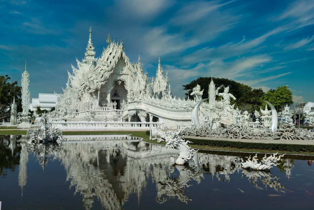 Beautiful detailed architecture of Wat Rong Khun temple in Chiang Rai with clear reflection.