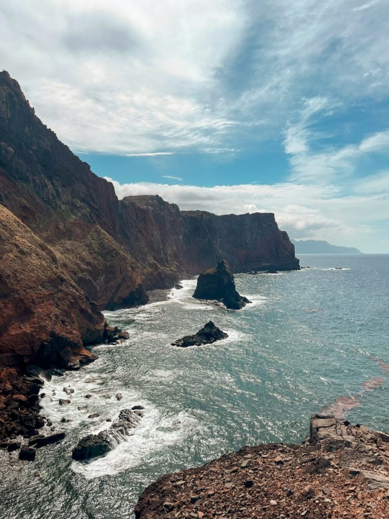 A rocky cliff overlooks the ocean on a cloudy day