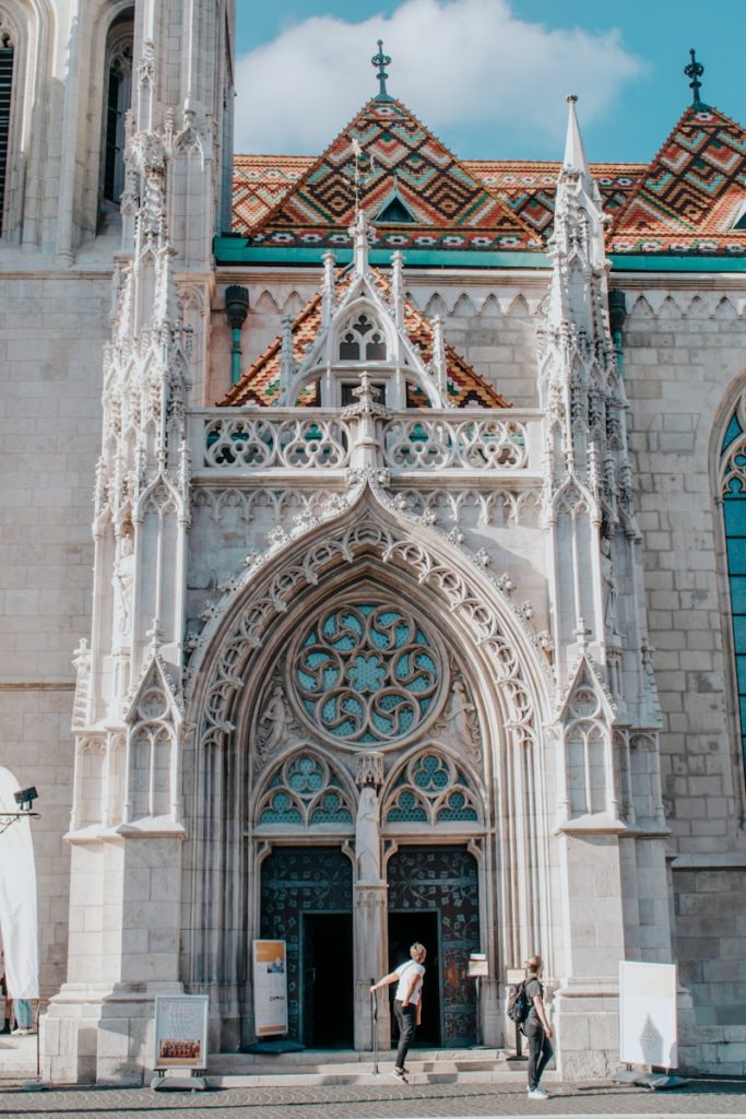 two people are standing outside of a large church