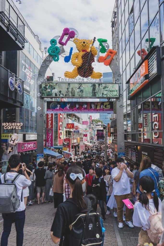 a crowd of people walking on a street with a large sign