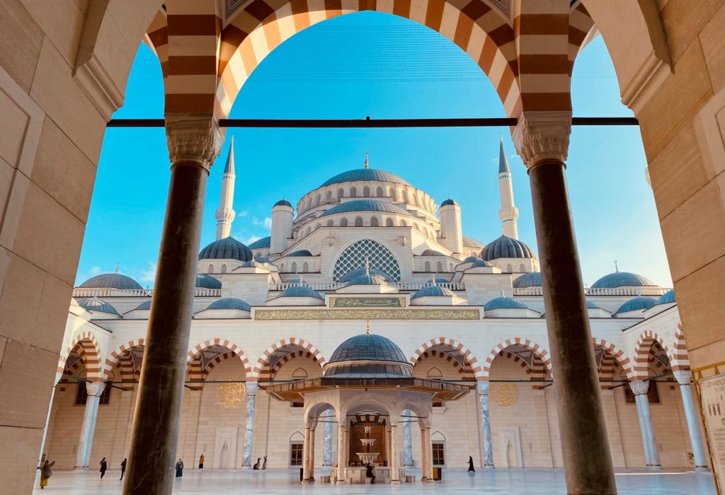 Stunning view of a grand mosque's courtyard in İstanbul, showcasing elegant domes and arches.