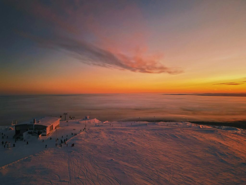 A breathtaking sunset over the snowy landscape of Ylläsjärvi, Finland, with soft clouds above and a serene winter atmosphere.