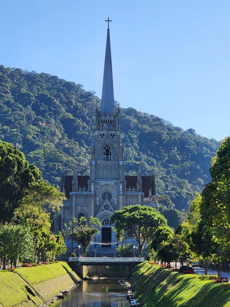 Stunning view of a Gothic cathedral nestled in a lush, green valley under clear skies.