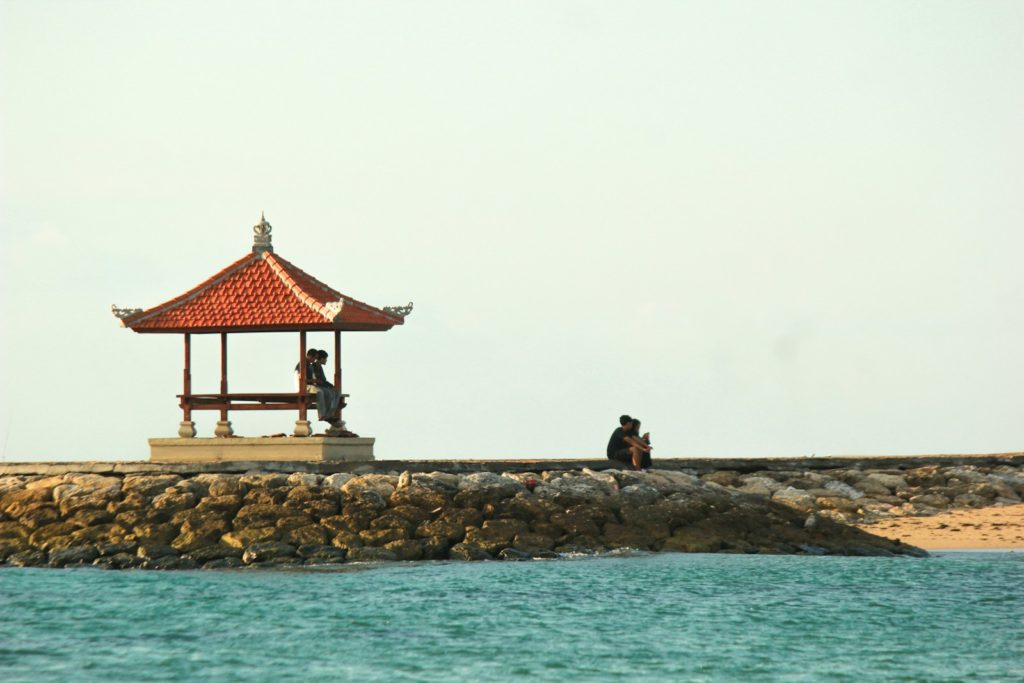 A couple of people sitting on a pier next to a body of water