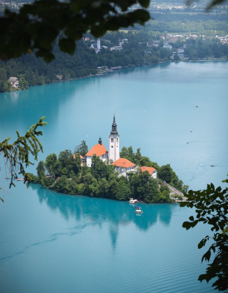 5 jours en Slovénie : itinéraire tranquille autour de Ljubljana 7 Picturesque aerial view of Lake Bled with iconic church on an island, lush green forests, and turquoise water.