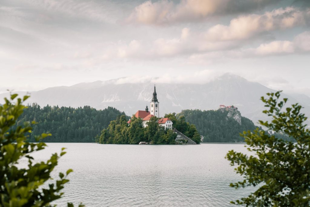 5 jours en Slovénie : itinéraire tranquille autour de Ljubljana 6 A picturesque view of Lake Bled with the iconic church on the island surrounded by mountains under a cloudy sky.